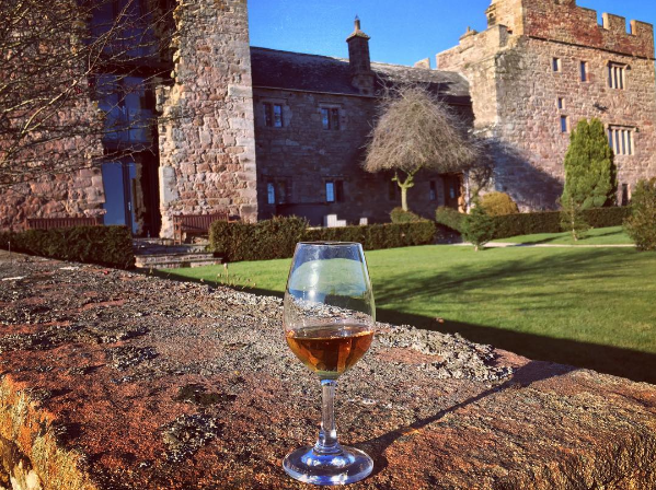 A dram of islay whisky in front of a castle