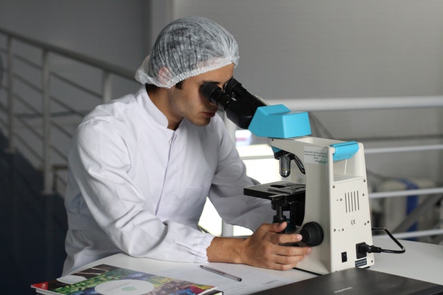 man in lab coart looking at microscope